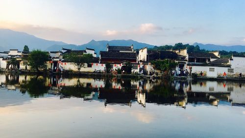 Scenic view of lake by buildings against sky