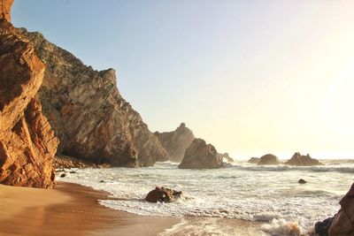 Rock formation on beach against clear sky