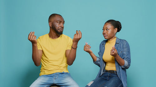 Man and woman gesturing against wall