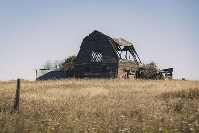 Abandoned house on field against clear sky