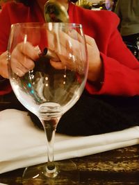 Close-up of hand holding wineglass on table