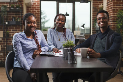 Portrait of smiling friends sitting at restaurant