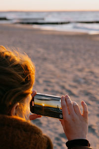 Side view of woman using mobile phone at beach
