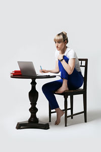 Young woman using laptop while sitting on sofa at home