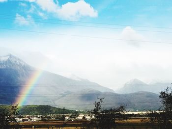 Scenic view of rainbow over mountains against sky