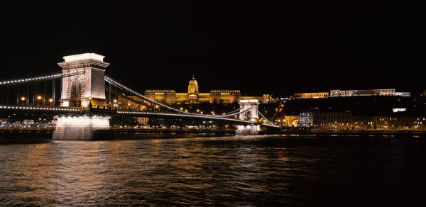 Illuminated bridge over river at night