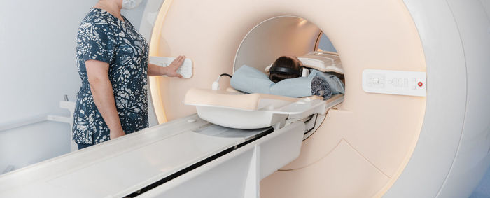 Doctor or nurse and patient with tomography ct or mri scan in hospital. interior of radiography