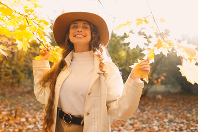 Portrait of young woman wearing hat standing on field