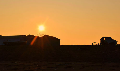 Boats moored on field against clear sky at sunrise