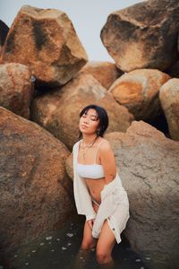 Sensuous young woman standing against rocks