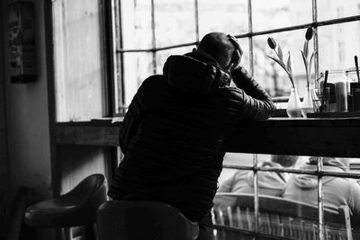 Rear view of man sitting on chair in cafe