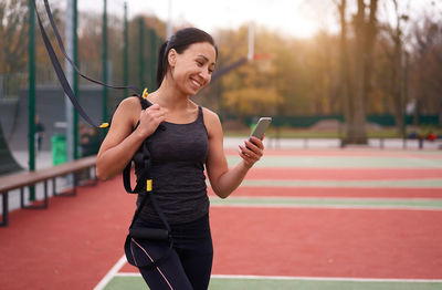 Smiling woman using mobile phone while standing outdoors