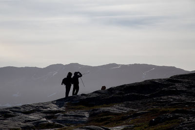 People standing on rock against sky