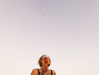 Woman holding drink against clear sky
