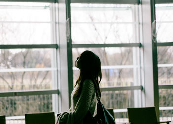 Side view of woman standing by window