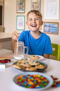 Portrait of smiling boy eating cookies at home