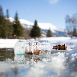 Close-up of bottle by water against sky