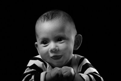 Portrait of cute boy against black background