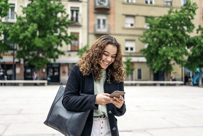 Young woman using mobile phone in city