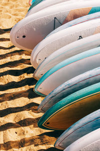 Close-up of colorful paddle boards for rent lying on the sand.