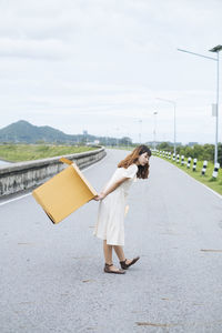 Woman standing on road against sky