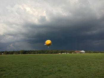 Blimp flying over grass against sky