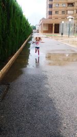 Rear view of girl walking on puddle