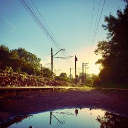 Electricity pylon by trees against sky