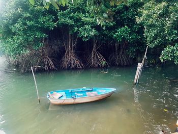 Boat moored on lake by trees