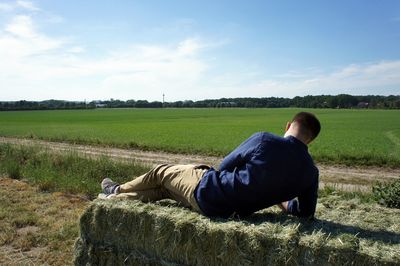 Man leaning on field against sky