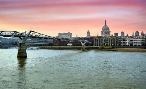 Bridge over river with buildings in background at sunset