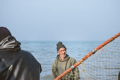 Portrait of friends on sea against clear sky