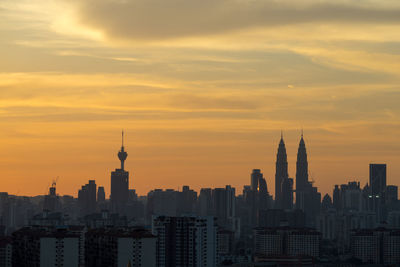 Skyscrapers in city against cloudy sky during sunset