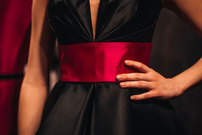 Female fashion figure in black classy silky dress with pink belt on backstage. fashion shot