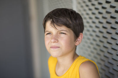 Close-up of smiling boy looking away by wall