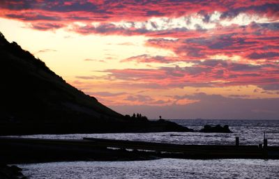 Scenic view of sea against dramatic sky during sunset