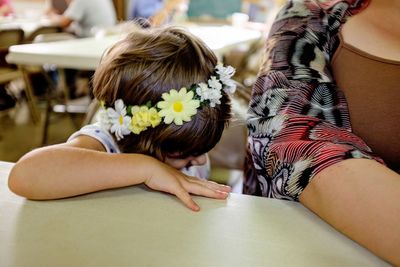 Cropped image of girl sitting by mother at table