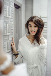 Young woman in bathrobe standing at bathroom