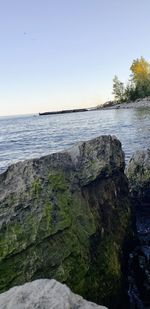 Rocks by sea against clear sky