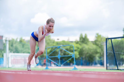 Full length of young woman exercising on field