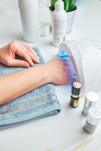 Woman applying gel hybrid polish using uv lamp. beauty wellness spa treatment concept. cosmetic