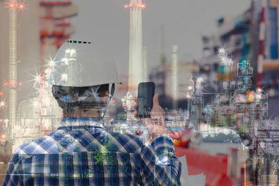 Rear view of man looking at city seen through glass