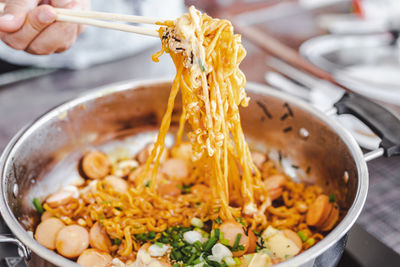 Close-up of hand holding noodles in plate