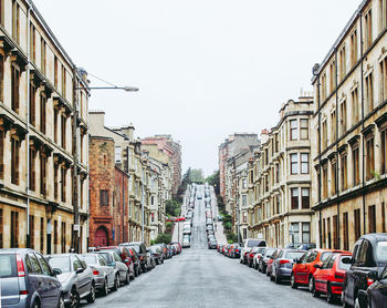 Cars parked on road amidst buildings against clear sky