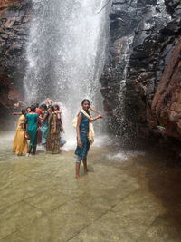 Group of people on rock formation in water