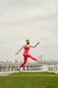 Full length of young woman jumping against built structure