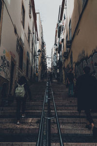 People walking on railroad tracks amidst buildings in city