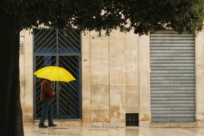 Man with yellow umbrella walking on the street