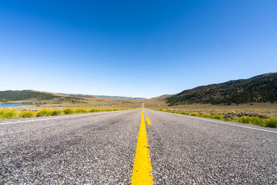 Surface level of road against clear blue sky