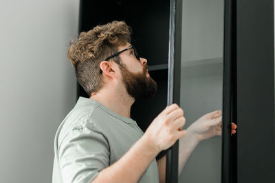 Young man looking through window